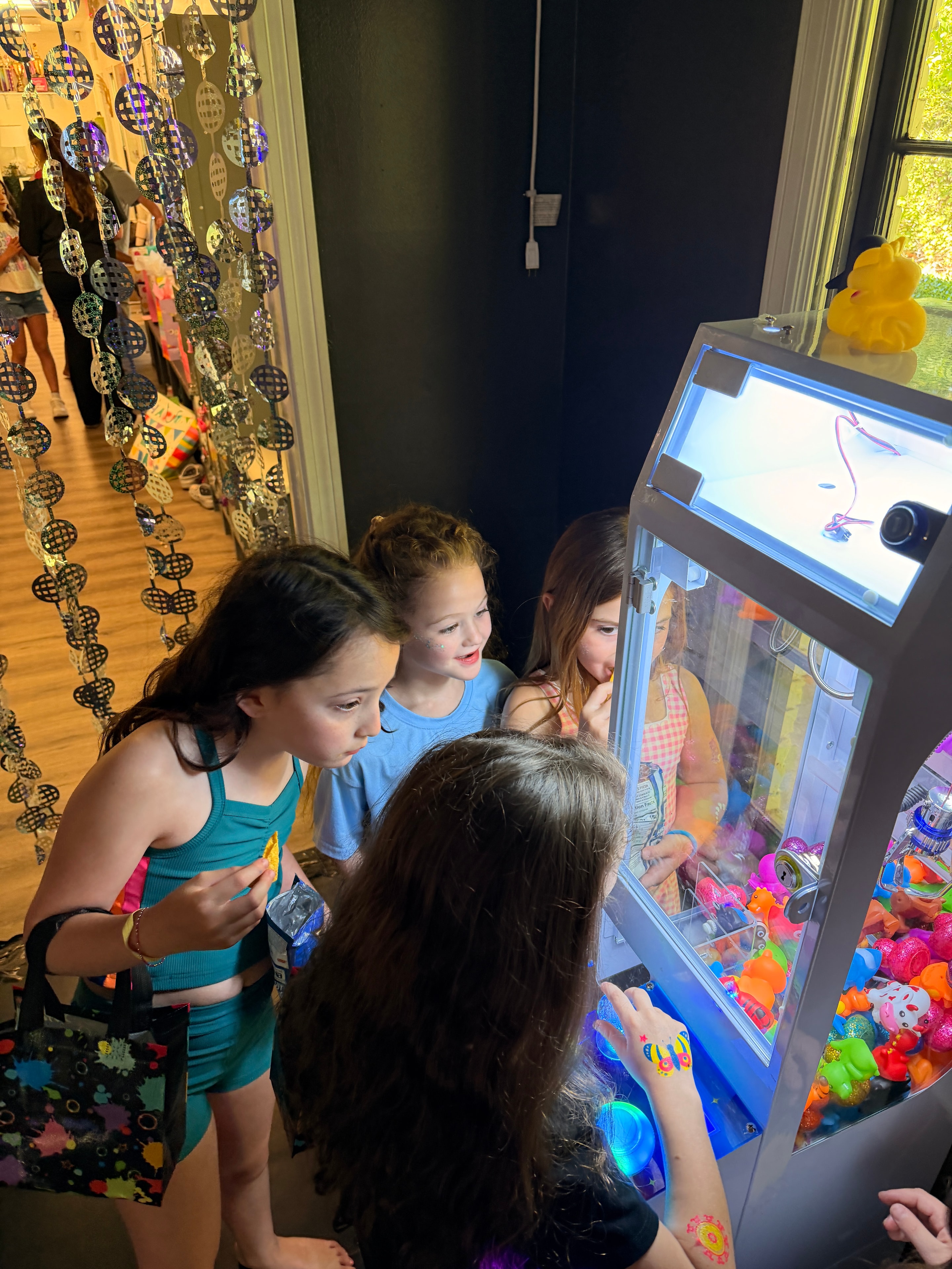 Kids peering into the crane game machine at a party